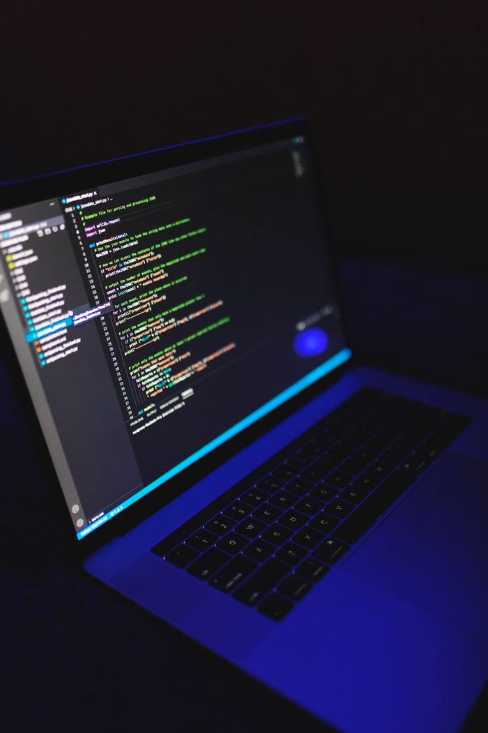 Services-02 A laptop showcasing colorful code in a dark environment, ideal for tech or programming content.